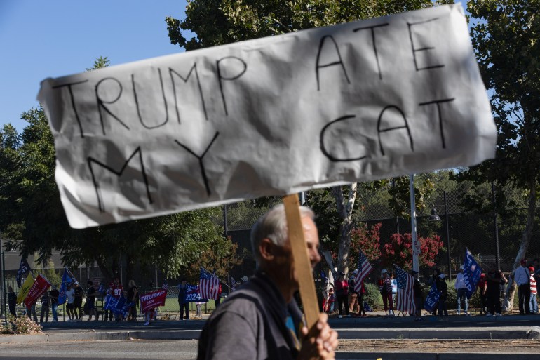 A counterprotester holds up a handwritten picket sign that reads, "Trump Ate My Cat."