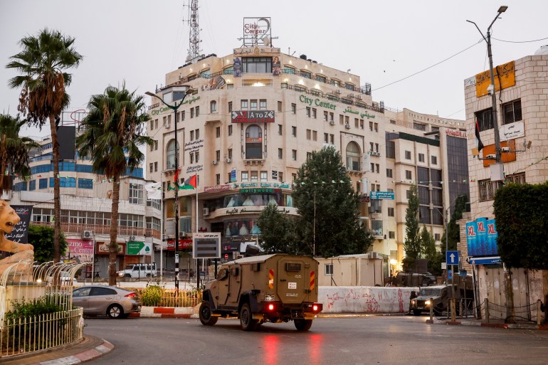 a military vehicle drives near an office building