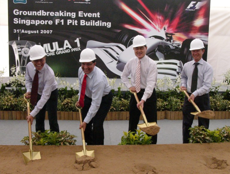 Ong Beng Seng and S Iswaran and two other officials use gold coloured shovels to break ground for the F1 pit building. Ong and Iswaran are on the left of the photo laughing. 