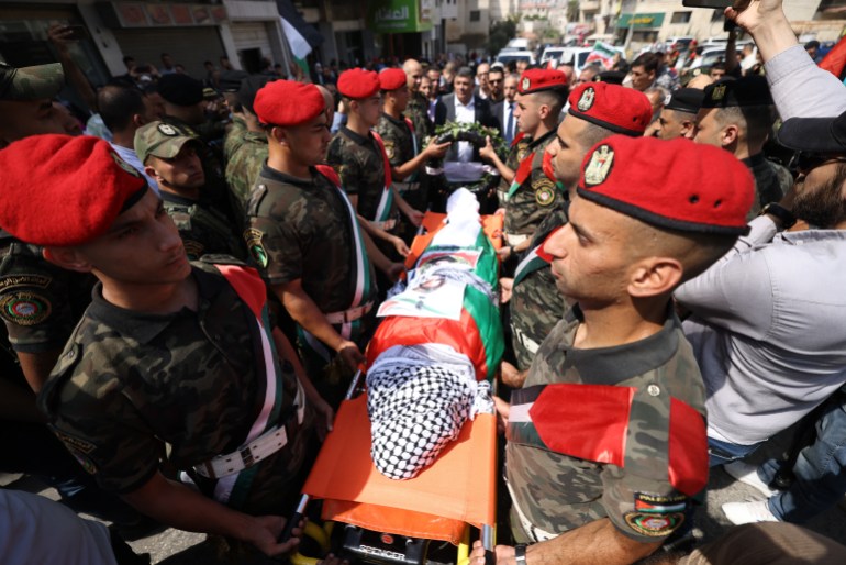 Palestinian security forces carry the body of slain Turkish-American activist Aysenur Ezgi