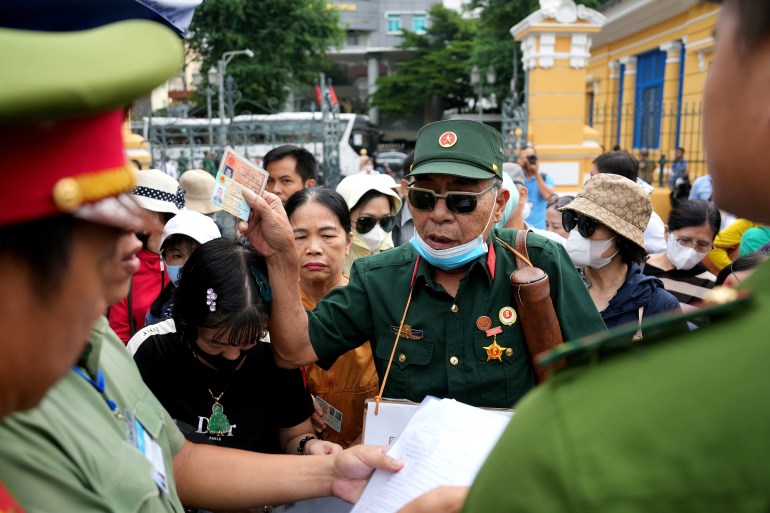 A Vietnam war veteran and fraud victim (C) arrives with other victims to attend the court proceedings of Vietnamese property tycoon Truong My Lan 