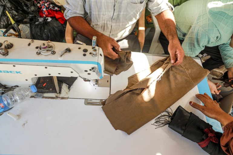 View of a tailor's hands and sewing machine as he alters a garment