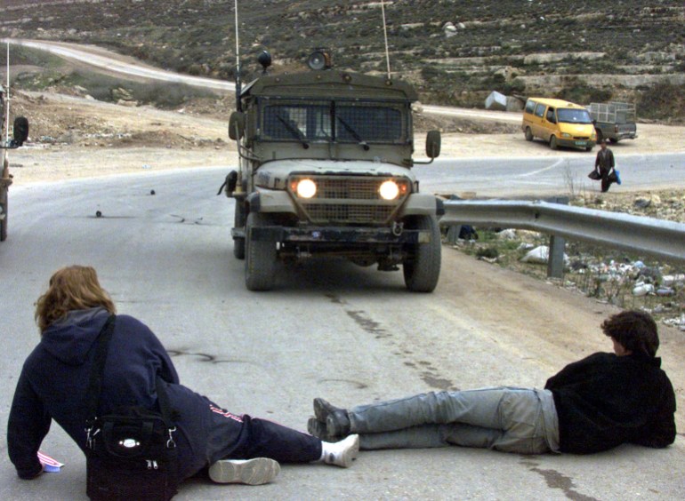 International activists lay in front of an Israeli jeep. 