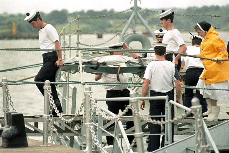 An officer watches as Irish sailors and rescue workers carry ashore the body of one of the 329 victims of the Air India Flight 182 jumbo jet which crashed in the Atlantic Ocean off Cork, Ireland June 24, 1985. A bomb exploded on the Air India flight as it flew over the Irish coast from Canada on June 23, 1985. REUTERS/Rob Taggart (IRELAND)