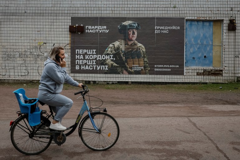 A local resident rides a bike near a recruitment advert for the Ukrainian army, amid Russia's attack on Ukraine, in the village of Hrushivka, Dnipropetrovsk region, Ukraine June 14, 2023. REUTERS/Alina Smutko