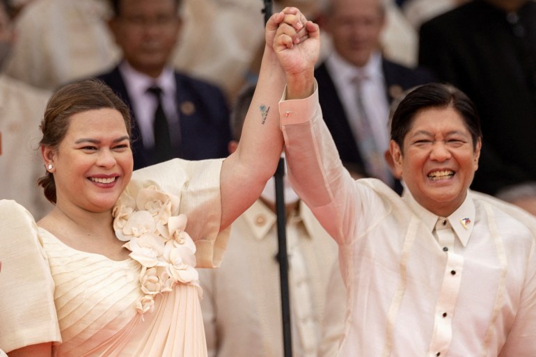 Vice President Sara Duterte and President Ferdinand Marcos Jr standing together after the election. They are raising their hands together and smiling. 