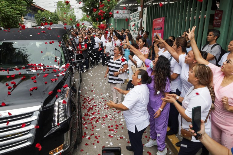 Mourners throw petals on a black vehicle carrying Alejandro Arcos's remains.