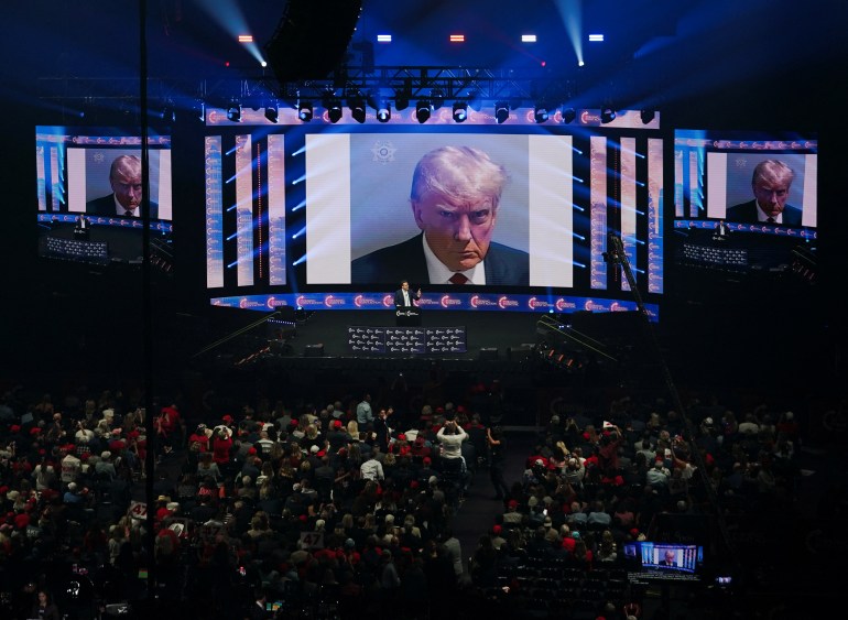 The mugshot of Republican presidential nominee and former U.S. President Donald Trump is displayed on screens at a campaign event for Trump 