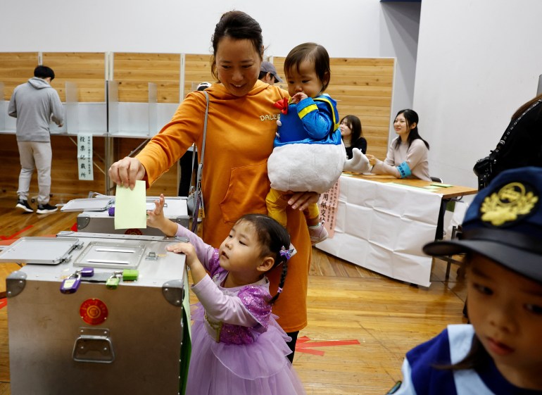 A woman accompanying her children in Halloween costume casts her ballot in the general election at a polling station in Tokyo