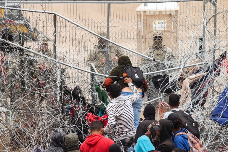 A group of migrant people try to cross a barbed wire fence to reach the US side, as seen from Ciudad Juarez, Mexico on March 20