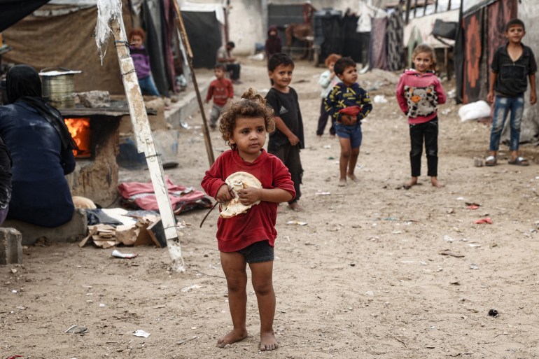 A Palestinian girl carries a freshly baked loaf of bread at a make-shift camp for the internally displaced in Deir al-Balah in the central Gaza Strip on October 17