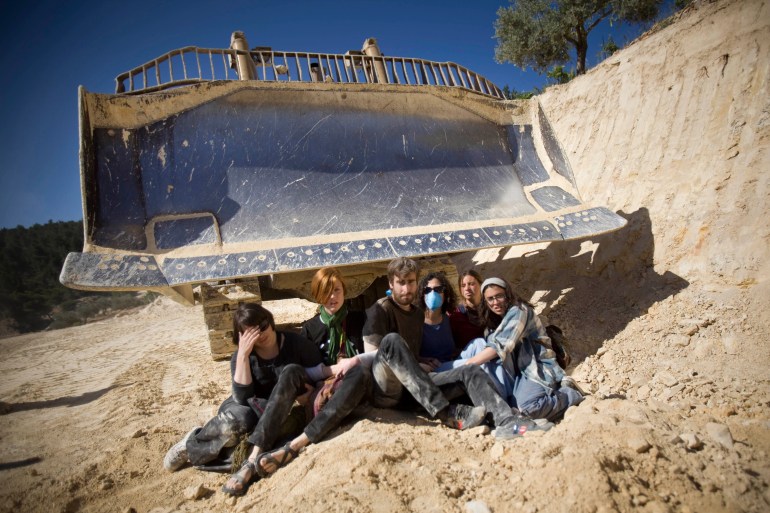 Israeli and international activists prevent a bulldozer to work during a protest.