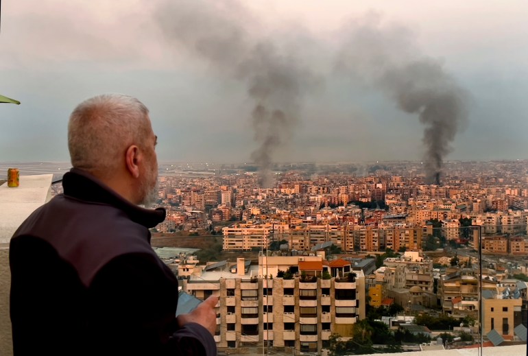 A man looks as smoke rise from Israeli airstrikes in Dahiyeh, Beirut,