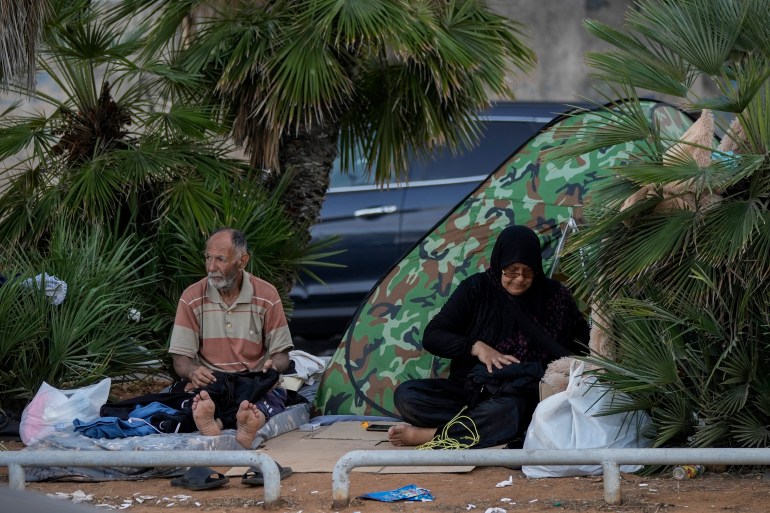 A displaced family fleeing the Israeli airstrikes in the south, sits on a sidewalk on Beirut's corniche, Lebanon, Monday, Oct. 14