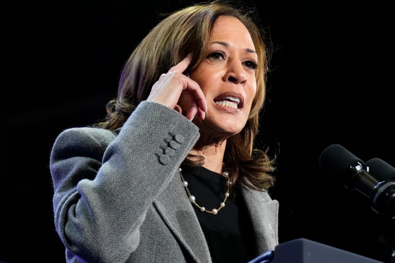 Kamala Harris speaks, pointing to her head in gesture.