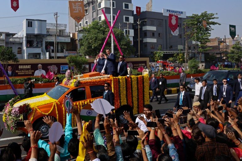 Indian Prime Minister Narendra Modi, center left, and his Spanish counterpart Pedro Sanchez, center right, wave to greet people from a vehicle in Vadodara, India, 