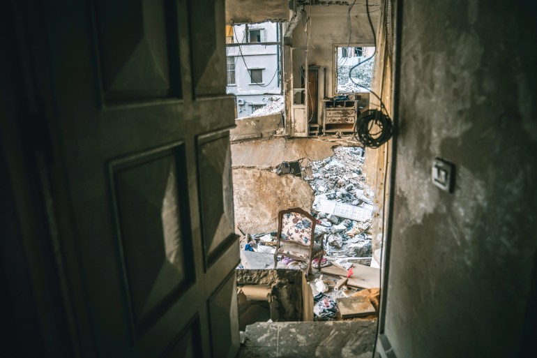 A chair hovers at the edge of the pit that Israel's bomb blew out in the building, destroying the floor below