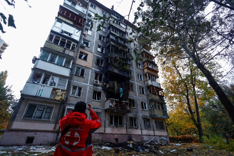 A Red Cross employee takes a picture of an apartment building damaged by a Russian drone strike in Kyiv on October 30 [Valentyn Ogirenko/Reuters]