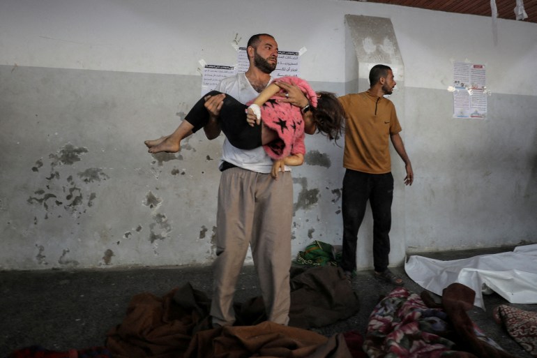 A man carries the dead body of a Palestinian girl killed in an Israeli strike on a house in Jabalia, at Al-Ahli hospital in Gaza City November 10, 2024