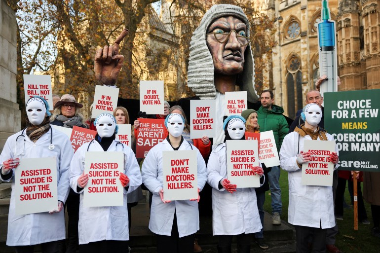 Protestors hold placards as they gather outside the Parliament as British lawmakers debate the assisted dying law