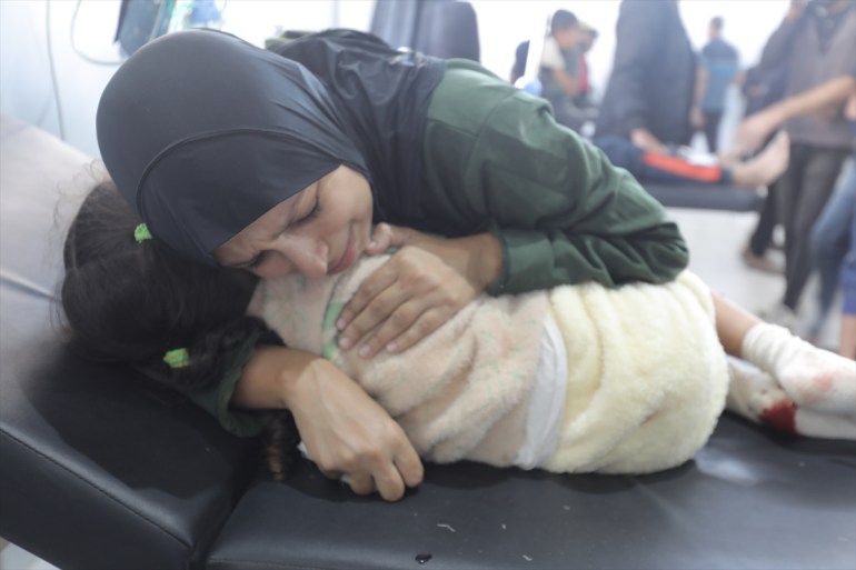 A woman embraces a child lying on a hospital bed