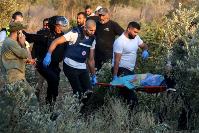 First responders carry the shrouded body of a woman who was killed when a rocket fired from Lebanon hit an area near Kiryat Ata in northern Israel's Haifa district on October 31, 2024, amid the ongoing war between Israel and Hezbollah. Israeli emergency services said a rocket launched from Lebanon killed two people in an olive grove in northern Israel on October 31, bringing the day's toll to seven dead. (Photo by AHMAD GHARABLI / AFP)