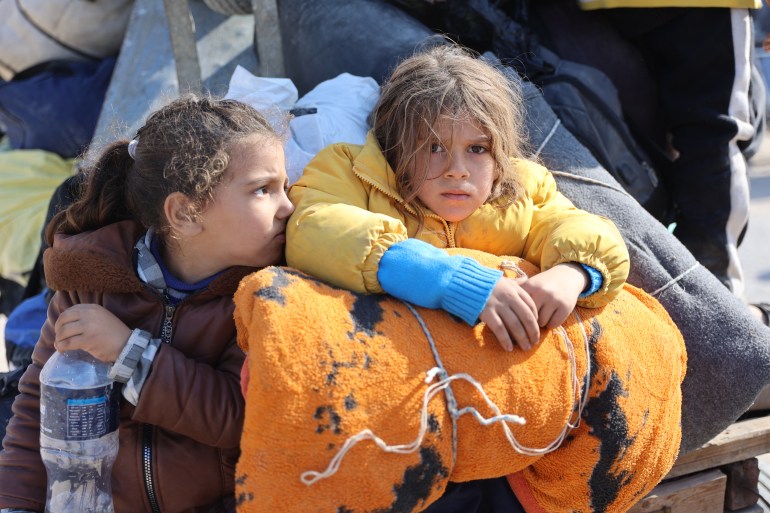 children sit with their belongings