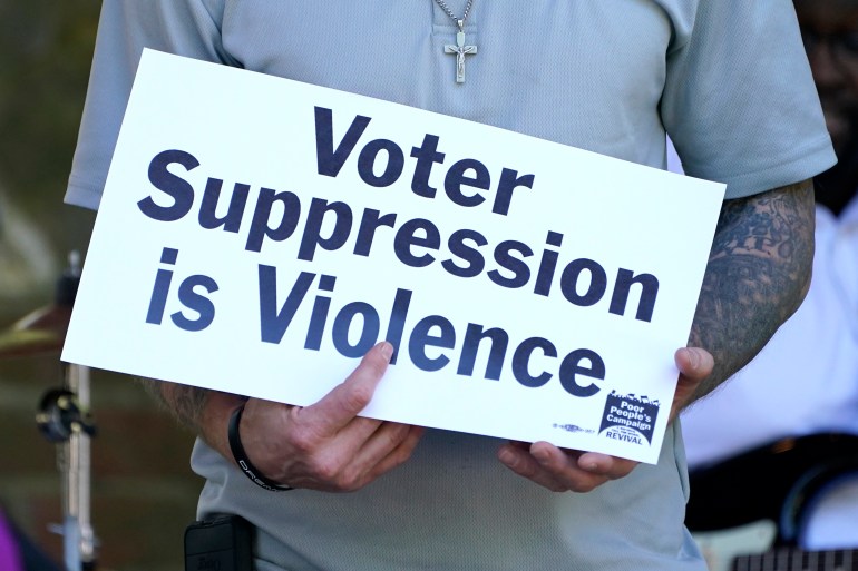 A person holds up a sign that reads, "Voter Suppression Is Violence."