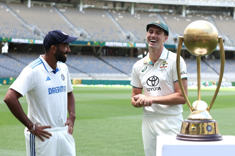 PERTH, AUSTRALIA - NOVEMBER 21: Jasprit Bumrah of India and Pat Cummins of Australia share a moment with the Border-Gavaskar Trophy during a media opportunity ahead of the series First Test Match between Australia and India at Optus Stadium on November 21, 2024 in Perth, Australia. (Photo by Paul Kane/Getty Images)