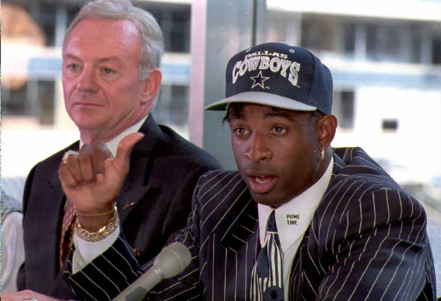 Deion Sanders talks to reporters at a press conference in Irving, Texas after the Dallas Cowboys signed him for "significant dollars." Cowboys owner Jerry Jones (L), who declined to release details of the contract said "Its a done deal."