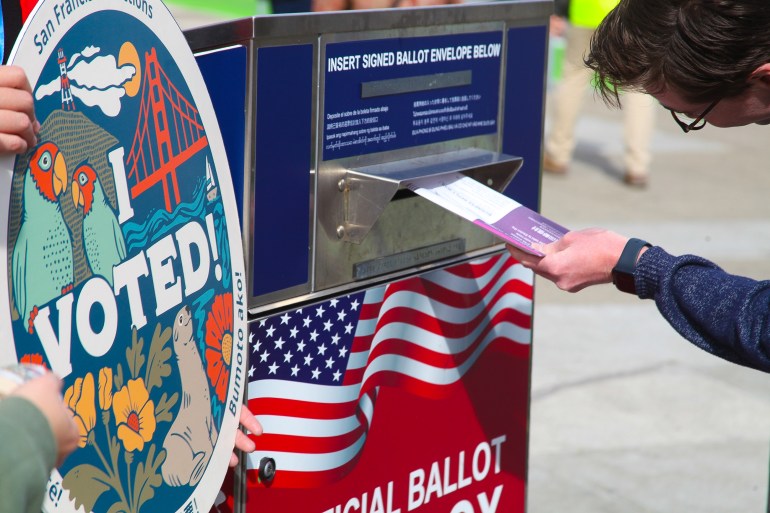 A voter puts a mail-in ballot in a drop box in San Francisco