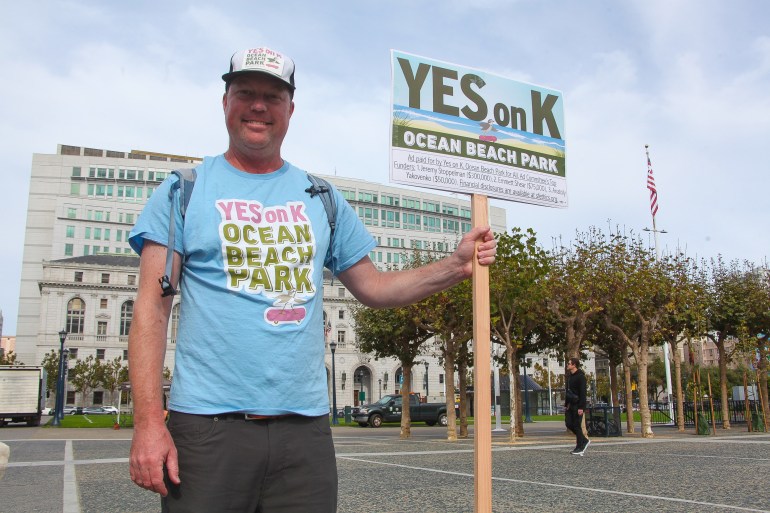 A voter holds up a sign in San Francisco that says, "Yes on K"