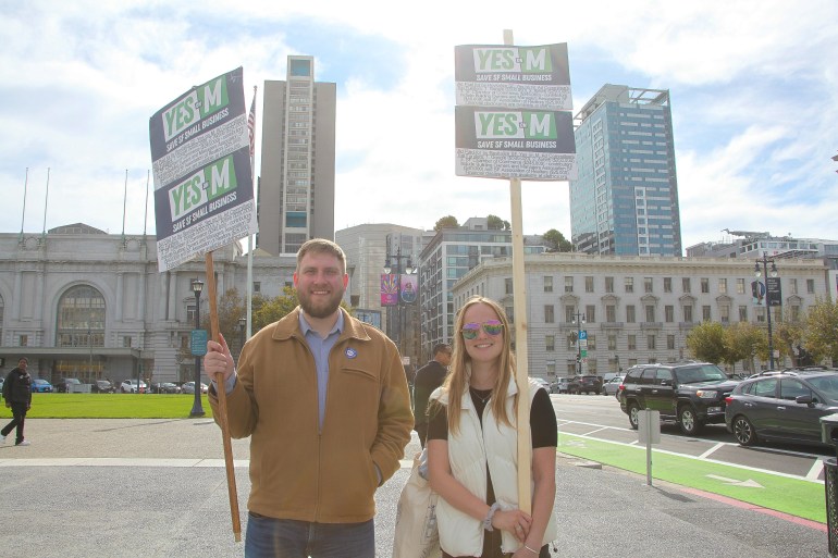 Two voters hold picket signs in front of San Francisco City Hall