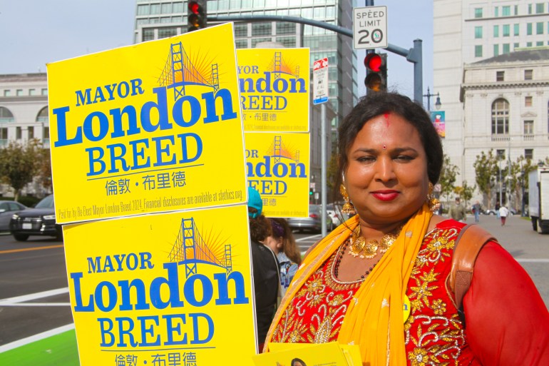 A supporter of London Breed, holding signs for her reelection campaign