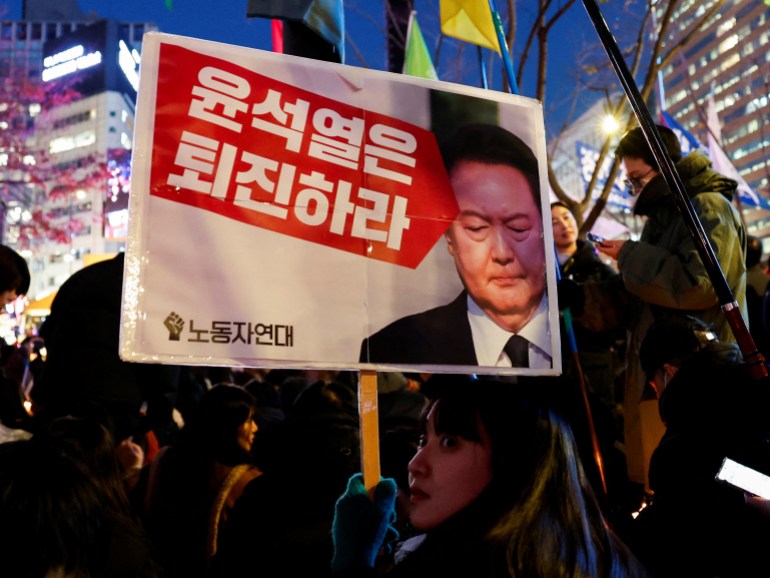 A protester holds a placard during a rally to condemn South Korean President Yoon Suk Yeol's surprise declaration of martial law last night, which was reversed hours later, and to call for his resignation, in Seoul, South Korea, December 4, 2024. The placard reads, "Step down Yoon Suk Yeol." REUTERS/Kim Kyung-Hoon