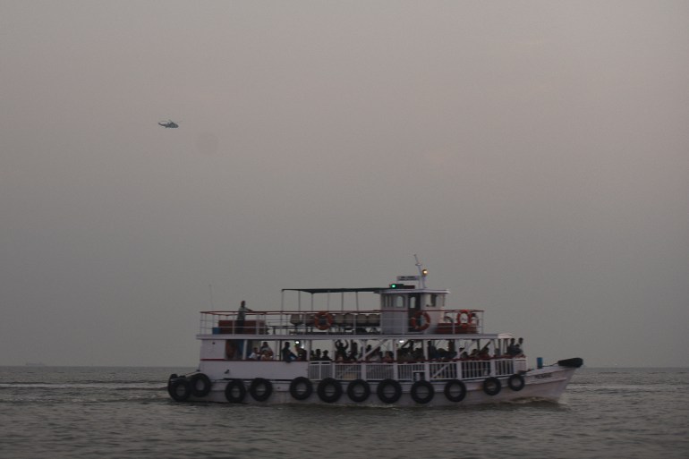 A military helicopter flies over a ferry during a rescue operation after a passenger boat capsized off the coast of India's financial capital Mumbai, India, December 18, 2024. REUTERS/Stringer