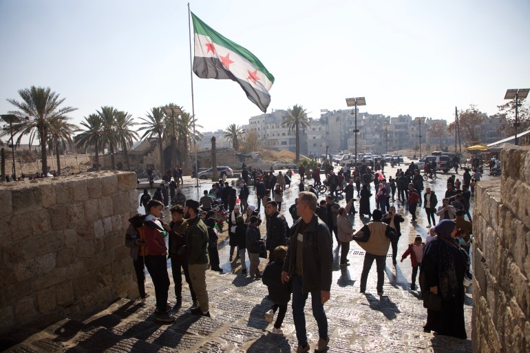 The Syrian flag waves near the historic Aleppo citadel [Ali Haj Suleiman/Al Jazeera]