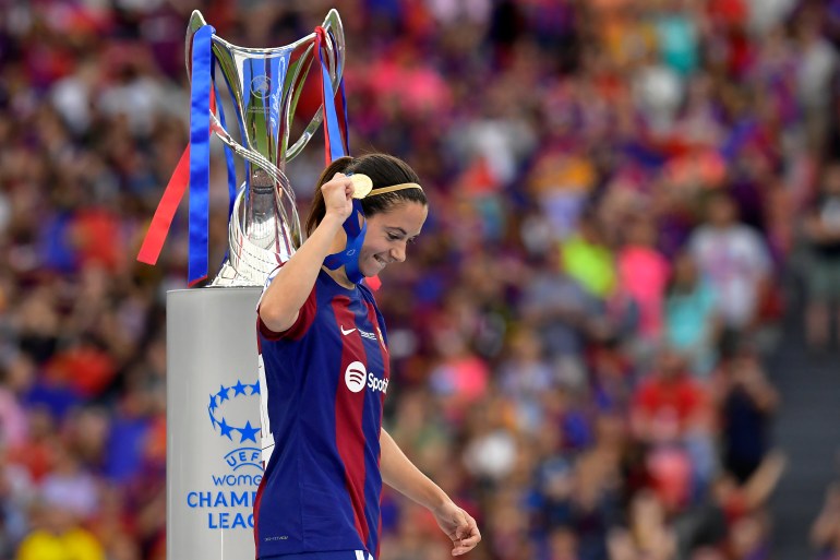 Barcelona's Aitana Bonmati holding up her medal walks past the trophy after winning the women's Champions League final soccer match between FC Barcelona and Olympique Lyonnais at the San Mames stadium in Bilbao, Spain, Saturday, May 25, 2024. Barcelona won 2-0. (AP Photo/Alvaro Barrientos)