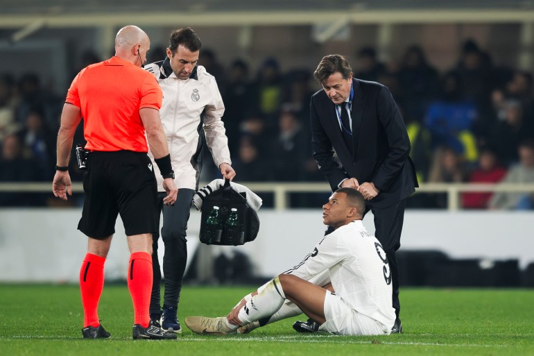 Kylian Mbappe sits on ground with leg injury.