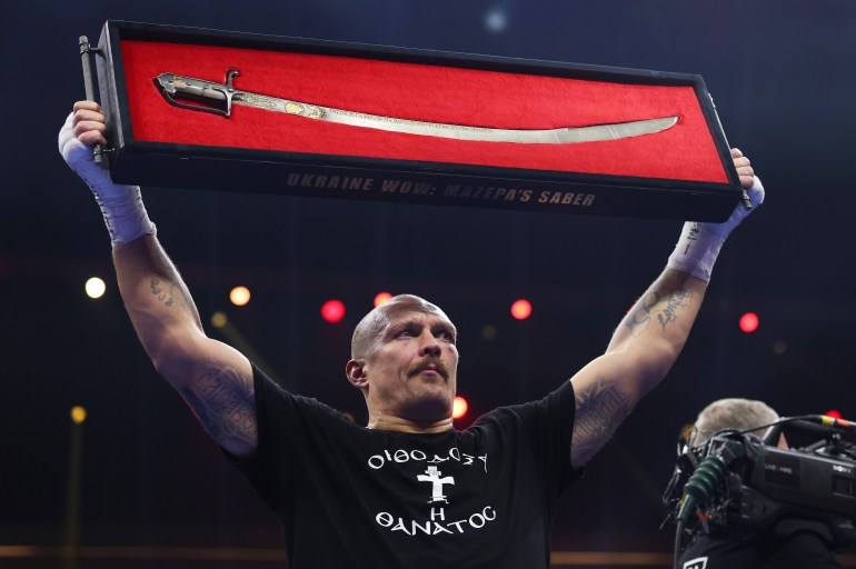 RIYADH, SAUDI ARABIA - DECEMBER 21: Oleksandr Usyk holds up a 'Ukraine Wow: Mazepa's Saber' following victory in the IBF, IBO, WBA, WBC and WBO Undisputed World Heavyweight titles' fight between Oleksandr Usyk and Tyson Fury as part of Oleksandr Usyk v Tyson Fury 2, Reignited card at Kingdom Arena on December 21, 2024 in Riyadh, Saudi Arabia. (Photo by Richard Pelham/Getty Images)